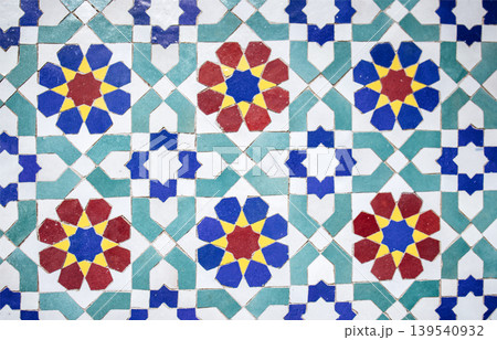Colorful geometric tile pattern featuring intricate floral designs in red, blue, yellow, and green, creating a vibrant and artistic visual texture for decorative purposes Colorful geometric tile pattern featuring intricate floral designs in red, blue, yellow, and green, creating a vibrant and artistic visual texture for decorative purposes 139540932