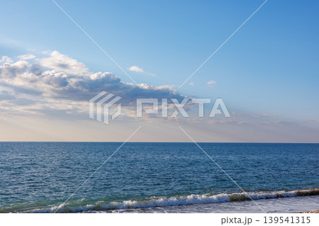 Blue sea waves with scattered clouds at sunset Blue sea waves with scattered clouds at sunset 139541315