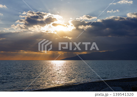 Sunlight rays breaking through clouds over a sea horizon 139541320