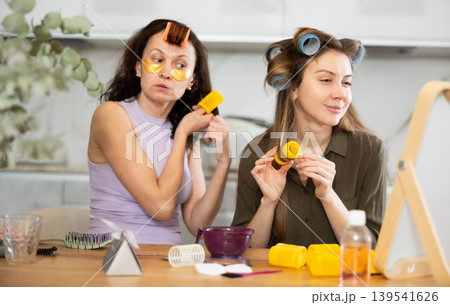 Two women curling their hair with curlers 139541626