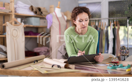 Female dressmaker working on digital sketch of dress in workshop 139541628
