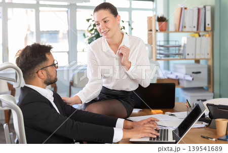 Adult business couple flirting at table at workplace in office Adult business couple flirting at table at workplace in office 139541689