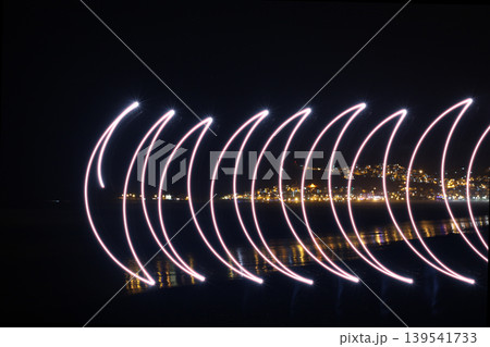 Abstract light painting trails over coastal city night skyline 139541733