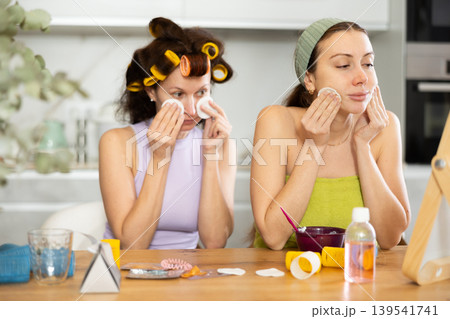 Two women cleanse their face with cotton pads Two women cleanse their face with cotton pads 139541741