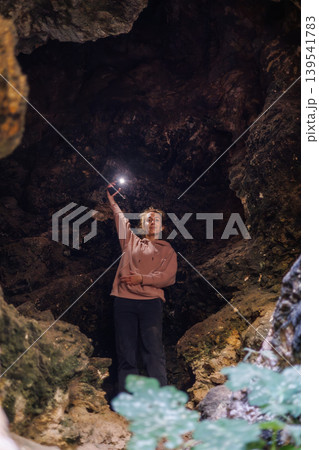 Woman holding flashlight in dark cave interior 139541783
