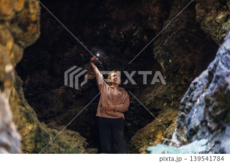 Woman holding flashlight in dark rocky cave Woman holding flashlight in dark rocky cave 139541784