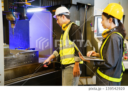 Industrial engineers operating machine control panel in factory environment 139542920