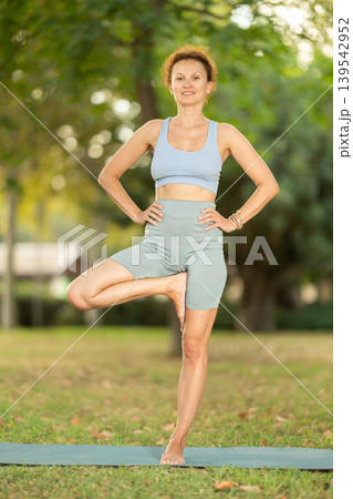 Adult woman doing yoga in tree pose Adult woman doing yoga in tree pose 139542952