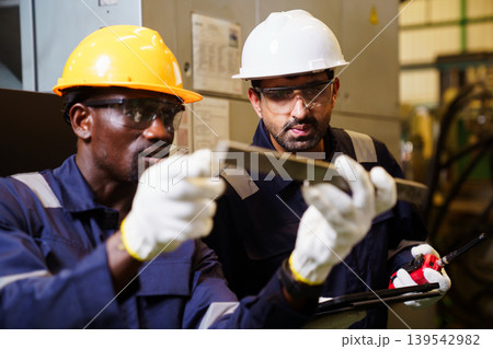 Engineers using tablet checking machinery in manufacturing factory 139542982