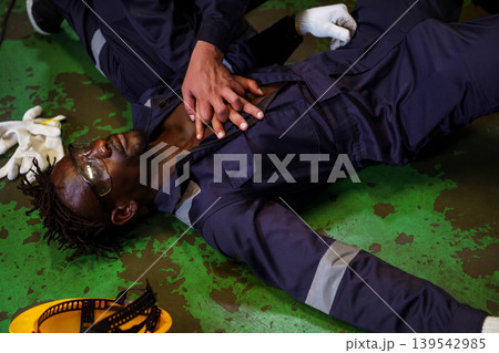 Emergency CPR by coworker after accident in industrial workplace 139542985