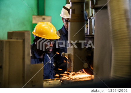 Factory workers grinding metal with sparks in industrial workshop 139542991
