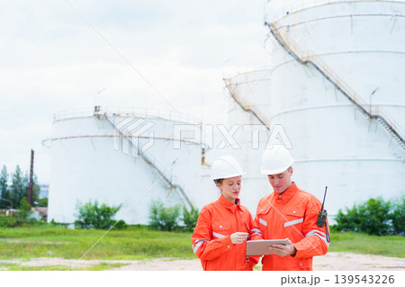 Two engineers surveying oil storage tank in energy plant 139543226