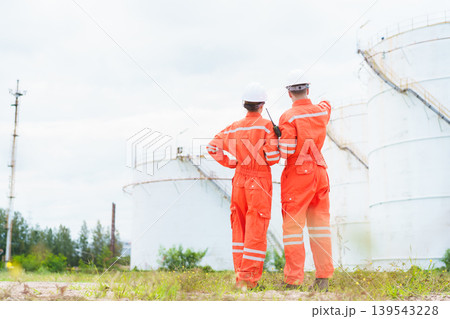 Two engineers surveying oil storage tank in energy plant Two engineers surveying oil storage tank in energy plant 139543228