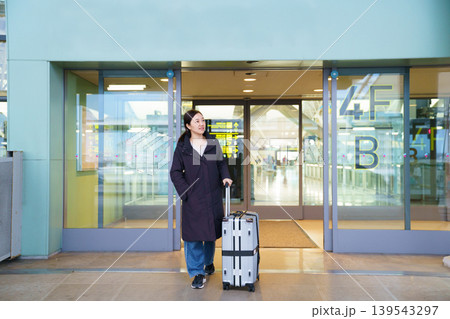 Asian woman with suitcase at airport terminal entrance 139543297