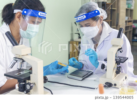 Scientist man woman working together team partner look into Microscope research in science laboratory. Two Asian scientist use microbiology microscope chemistry lab equipment. Biochemistry researcher Scientist man woman working together team partner look into Microscope research in science laboratory. Two Asian scientist use microbiology microscope chemistry lab equipment. Biochemistry researcher 139544005