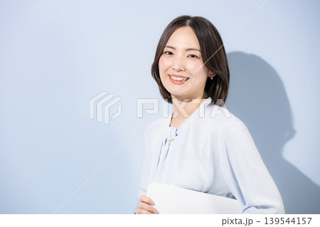 水色背景でパソコンを持つカメラ目線笑顔の女性のポジティブ、かわいい女性の信頼と自信 転職や採用 水色背景でパソコンを持つカメラ目線笑顔の女性のポジティブ、かわいい女性の信頼と自信 転職や採用 139544157
