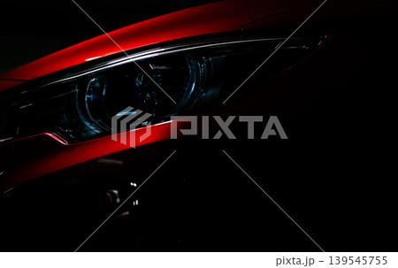 Closeup headlight of shiny red luxury SUV compact car. Elegant electric car technology and business concept. Hybrid auto and automotive concept. Car parked in showroom or motor show. Car dealership. Closeup headlight of shiny red luxury SUV compact car. Elegant electric car technology and business concept. Hybrid auto and automotive concept. Car parked in showroom or motor show. Car dealership. 139545755