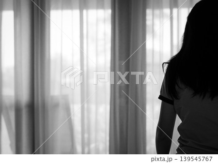Rear view of sad adult Asian woman sitting on bed in bedroom, stressed and depressed mood. Loneliness anxiety and postpartum depression, emotional struggle in home with mental health awareness. 139545767