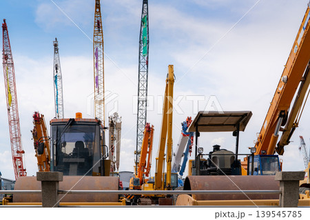 Road roller, mobile crane, and backhoe with long boom. Heavy machinery parked at second-hand machinery auction yard. Road roller, mobile crane, and digger for rent and sale. Construction industry. Road roller, mobile crane, and backhoe with long boom. Heavy machinery parked at second-hand machinery auction yard. Road roller, mobile crane, and digger for rent and sale. Construction industry. 139545785