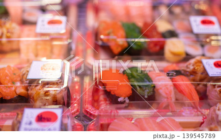 Sushi set in plastic box displayed on supermarket shelf representing Japanese takeaway food ready to eat in convenient disposable container for busy urban lifestyle and healthy meal choice. Sushi set in plastic box displayed on supermarket shelf representing Japanese takeaway food ready to eat in convenient disposable container for busy urban lifestyle and healthy meal choice. 139545789