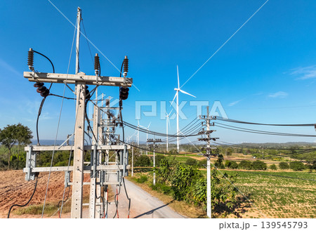 Electricity transmission tower under blue sky, collecting wind power from turbines in remote field. Clean energy infrastructure for sustainable development and grid connection. Renewable energy. 139545793