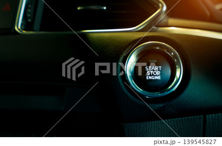 Start stop engine button of luxury car. Push up button for start or stop car engine in keyless automobile. Turn key with ignition system concept. Black ignition switch. Car dashboard interior view. 139545827