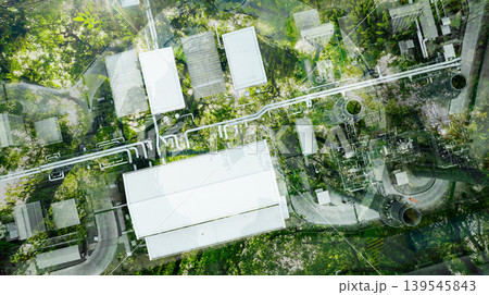 Aerial view factory roof amidst lush green tree forest. Sustainable practices for carbon reduction of factories. Sustainability in manufacturing. Carbon offsets and eco-friendly industrial practices. Aerial view factory roof amidst lush green tree forest. Sustainable practices for carbon reduction of factories. Sustainability in manufacturing. Carbon offsets and eco-friendly industrial practices. 139545843