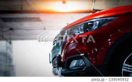 Selective focus on red shiny SUV sport car parked at shopping mall indoor parking lot. Headlamp lights with elegant and luxury design. Automotive industry and hybrid car concept. Underground parking. Selective focus on red shiny SUV sport car parked at shopping mall indoor parking lot. Headlamp lights with elegant and luxury design. Automotive industry and hybrid car concept. Underground parking. 139545932