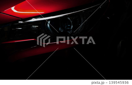 Closeup headlight of shiny red luxury SUV compact car. Elegant electric car technology and business concept. Hybrid auto and automotive concept. Car parked in showroom or motor show. Car dealership. 139545936