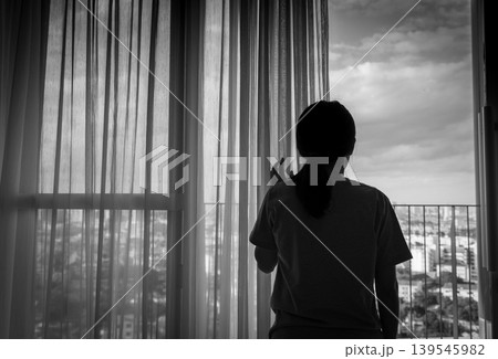 Sad woman looking out window with thoughtful expression, stressed and depressed mood in home or hospital. Loneliness anxiety mental health struggle, emotional wellbeing and psychological distress. Sad woman looking out window with thoughtful expression, stressed and depressed mood in home or hospital. Loneliness anxiety mental health struggle, emotional wellbeing and psychological distress. 139545982