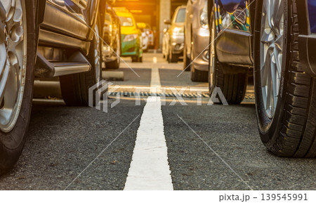Parking lot at airport or shopping mall with rows of parked cars, closeup of wheels in outdoor space. Car rental business, automotive industry, used car market and urban transport infrastructure. Parking lot at airport or shopping mall with rows of parked cars, closeup of wheels in outdoor space. Car rental business, automotive industry, used car market and urban transport infrastructure. 139545991