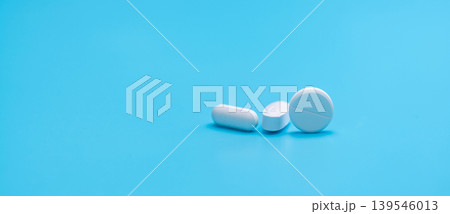 Round white tablets pills and oval tablets pills on blue background. Pharmacy shop banner. Prescription drugs. Pharmaceutical industry. Painkiller, antibiotics, and antacid tablet pills. Pharmaceutic. 139546013