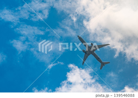 Commercial airline flying on blue sky and white fluffy clouds. Under view of airplane flying. Passenger plane after take off or going to landing flight. Vacation travel abroad. Air transportation. Commercial airline flying on blue sky and white fluffy clouds. Under view of airplane flying. Passenger plane after take off or going to landing flight. Vacation travel abroad. Air transportation. 139546088