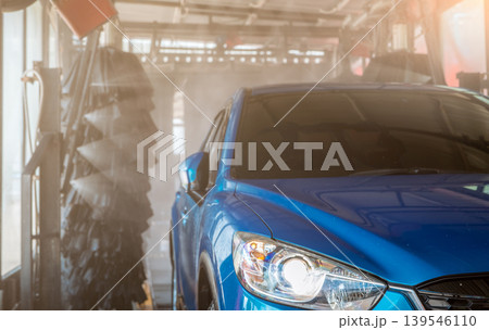 Blue SUV car washing by automatic car washing machine. Auto care. Car cleaning with high pressure water spray after clean by auto brush. Car cleaning before waxing service. Carwash service business. 139546110