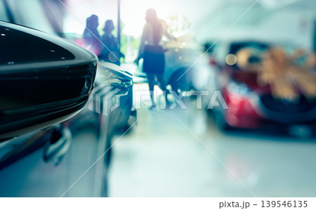 Selective side mirror car on blur saleswoman and customer in modern luxury showroom. Car dealership office concept. Dealer agent business. Automobile leasing service. Dealer company. New car purchase. 139546135