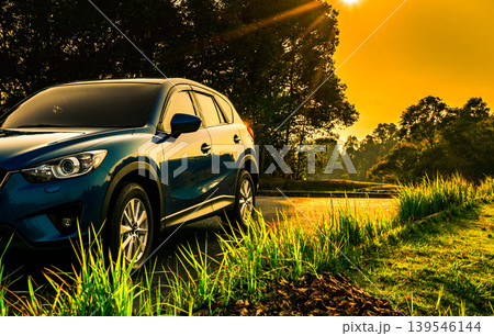Blue compact SUV car with modern sport design parked in parking lot at sunrise, eco friendly hybrid electric vehicle concept. Sustainable transport technology, business success and travel lifestyle. 139546144