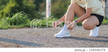 Young Asian woman tying running shoes in the park. Female runner getting ready for jogging and exercise on the road. Fitness, wellness and outdoor sport concept in morning Young Asian woman tying running shoes in the park. Female runner getting ready for jogging and exercise on the road. Fitness, wellness and outdoor sport concept in morning 139546179
