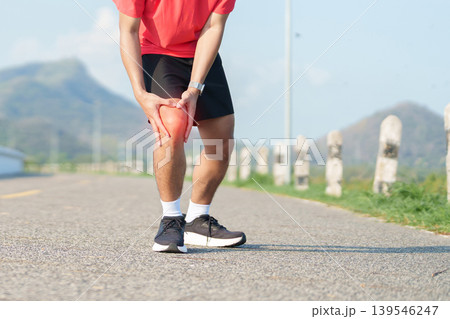 Young adult male runner with knee pain from ACL injury or patellofemoral syndrome. Man having joint ache, ligament tear or patellar tendinitis during running. Sports medical and healthcare concept Young adult male runner with knee pain from ACL injury or patellofemoral syndrome. Man having joint ache, ligament tear or patellar tendinitis during running. Sports medical and healthcare concept 139546247