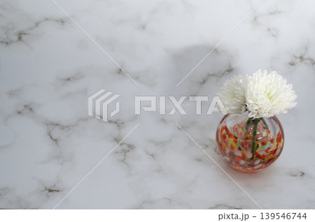 明るい背景で暖色硝子球形一輪挿に白色い菊(右配置) 139546744