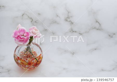暖色球形ガラス一輪挿しに挿した桃色のカーネーションの花とつぼみ(左配置) 暖色球形ガラス一輪挿しに挿した桃色のカーネーションの花とつぼみ(左配置) 139546757
