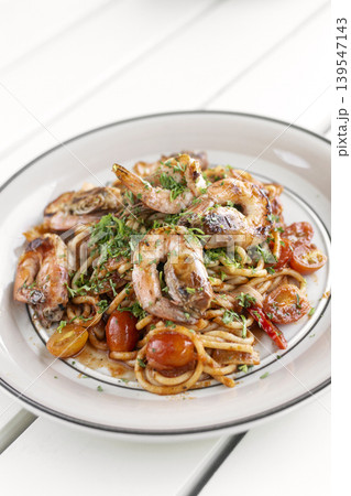 shrimp and tomato diavolo spicy spaghetti on white table at outdoor restaurant in italy 139547143