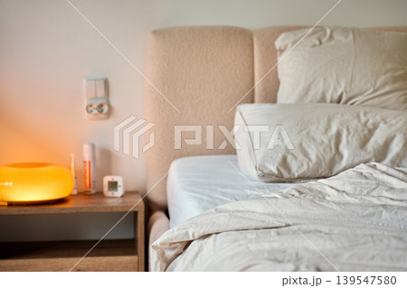 Unmade bed with bedside lamp in cozy bedroom Unmade bed with bedside lamp in cozy bedroom 139547580