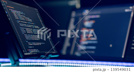 Software engineering workspace. Multiple screens showing complex coding script in dark mode, illuminated by glowing blue LED light. Cybersecurity concept. Software engineering workspace. Multiple screens showing complex coding script in dark mode, illuminated by glowing blue LED light. Cybersecurity concept. 139549031