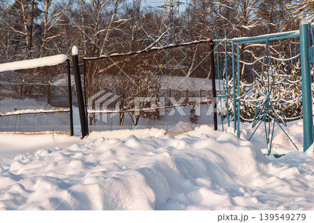 Deep snowdrifts pile high beside a dark fence line on a crisp winter afternoon as low sunlight bathes the scene in a warm glow Deep snowdrifts pile high beside a dark fence line on a crisp winter afternoon as low sunlight bathes the scene in a warm glow 139549279