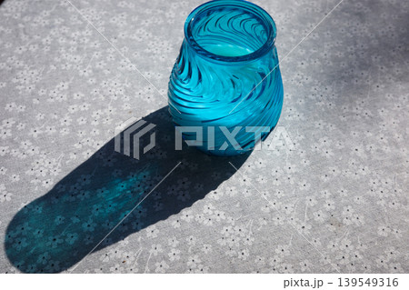 Blue Glass Vase On Patterned Tablecloth With Sunlight Shadow 139549316
