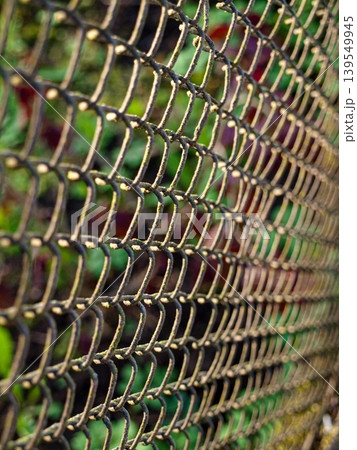 Texture of an old rusty chain link mesh fence. Iron wire network pattern with aged metallic details and corrosion. Vintage industrial background of a metal safety grid outdoor. Geometric grid Texture of an old rusty chain link mesh fence. Iron wire network pattern with aged metallic details and corrosion. Vintage industrial background of a metal safety grid outdoor. Geometric grid 139549945