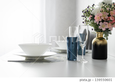 Modern dining table setting with flowers in bright apartment interior Modern dining table setting with flowers in bright apartment interior 139550601
