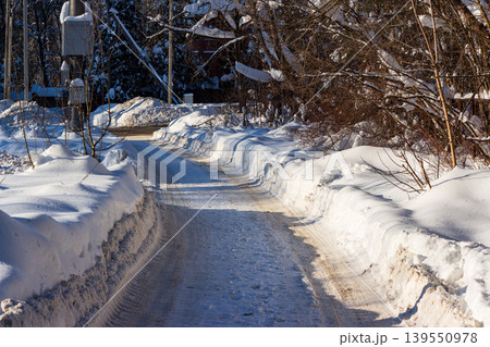 Narrow snowy road winding through deep winter banks under bright sunlight Narrow snowy road winding through deep winter banks under bright sunlight 139550978