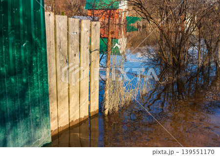 Spring floods inundate dacha plots and houses in Russia, submerging yards and fences with murky water. The scene captures the raw power of nature and the vulnerability of rural homes. Spring floods inundate dacha plots and houses in Russia, submerging yards and fences with murky water. The scene captures the raw power of nature and the vulnerability of rural homes. 139551170