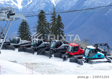 Several snowcats in a picturesque ski resort against the backdrop of beautiful mountains Several snowcats in a picturesque ski resort against the backdrop of beautiful mountains 139551203